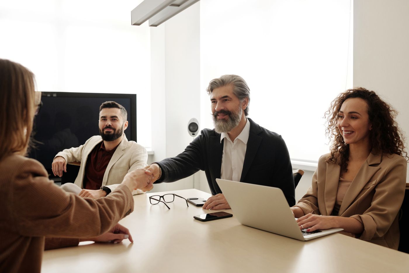 Colleagues shaking hands across a meeting table